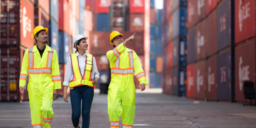 Group of engineers working with laptop in the container yard. This is a freight transportation and distribution warehouse.