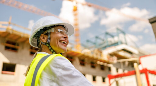 Professional female engineer in protective helmet against on construction background